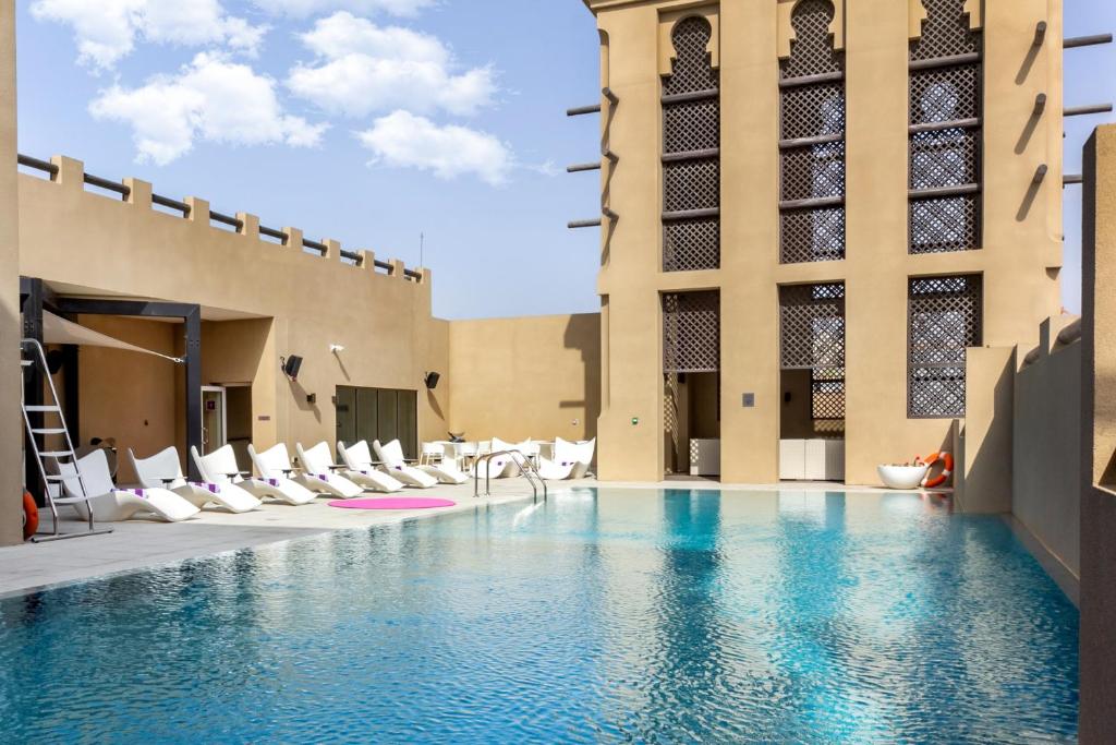 a pool in a building with white lounge chairs at Premier Inn Dubai Al Jaddaf in Dubai