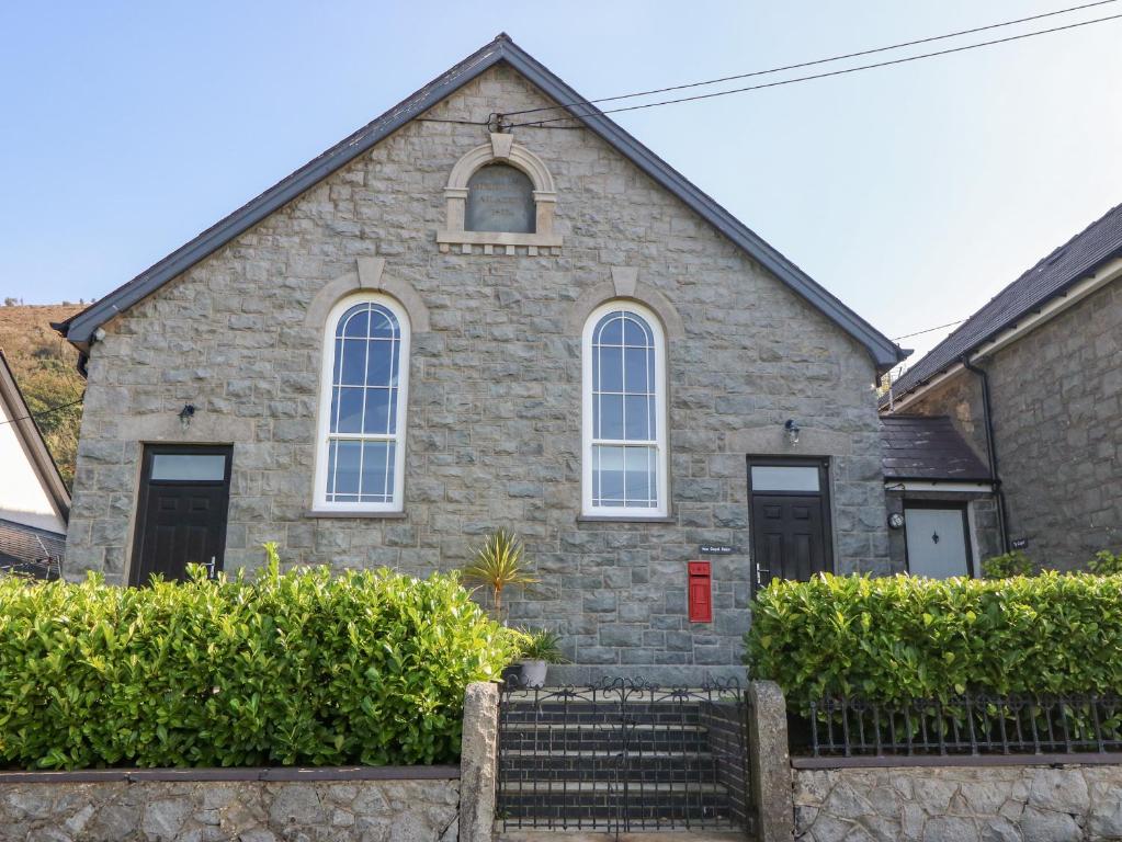 una iglesia de piedra con 3 ventanas y escaleras delante en Hen Gapel Seion en Caernarfon