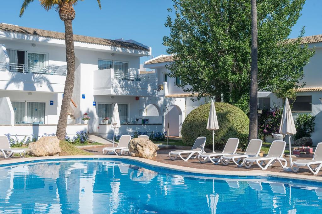 una piscina con tumbonas y un complejo en Apartamentos Solecito, en Puerto de Alcudia