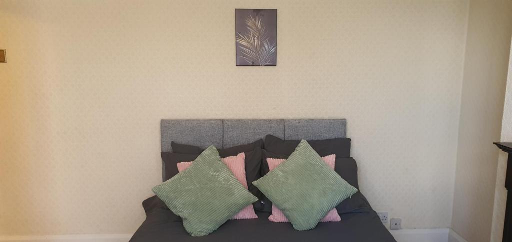 1 dormitorio con 1 cama con almohadas verdes y rosas en Coventry Spacious Rooms In City, en Coventry