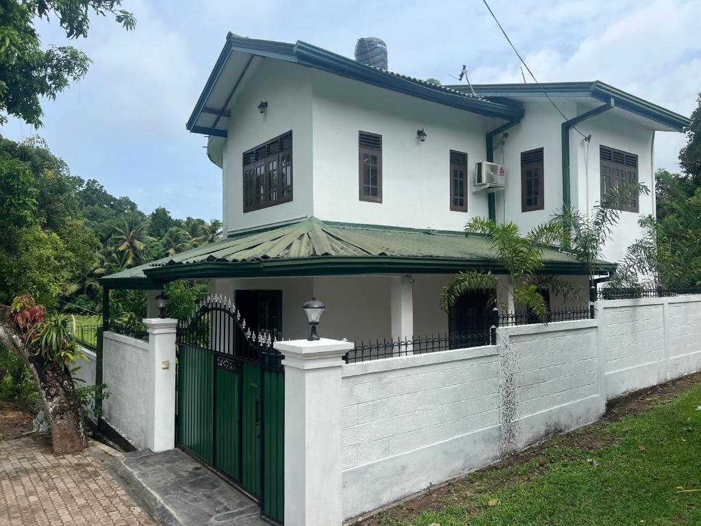 a white house with a green gate at Jas - Sri Lankan Villa in Polgasowita