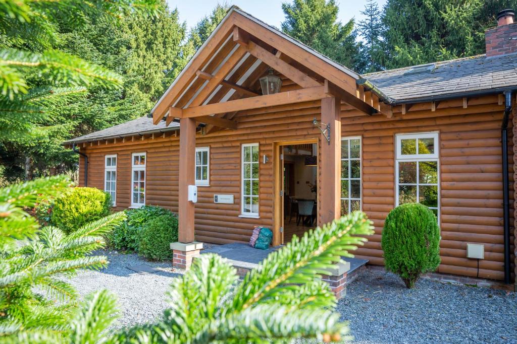 a small wooden cabin with a porch in a garden at The Hollies Forest Lodges in Cuddington