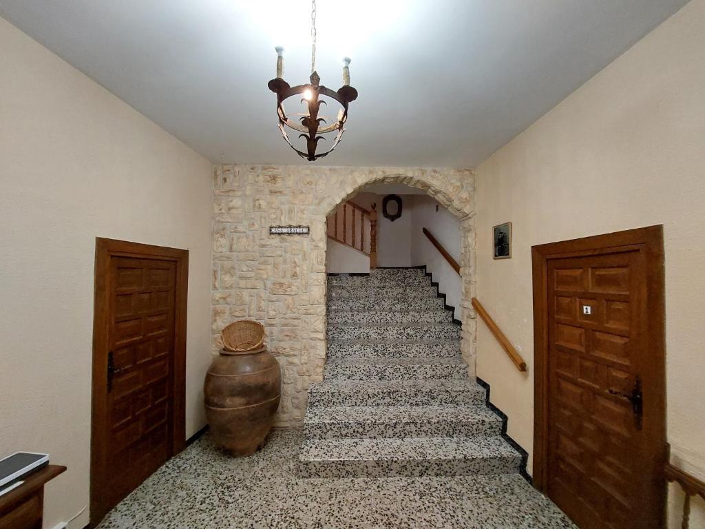 a hallway with a staircase in a building with a chandelier at Casa Rural Nueva Araceli in Oliete