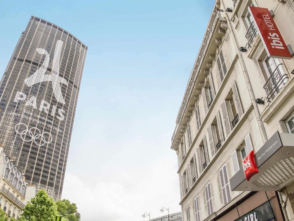 un grand bâtiment avec un panneau sur son côté dans l'établissement ibis Paris Tour Montparnasse 15eme, à Paris
