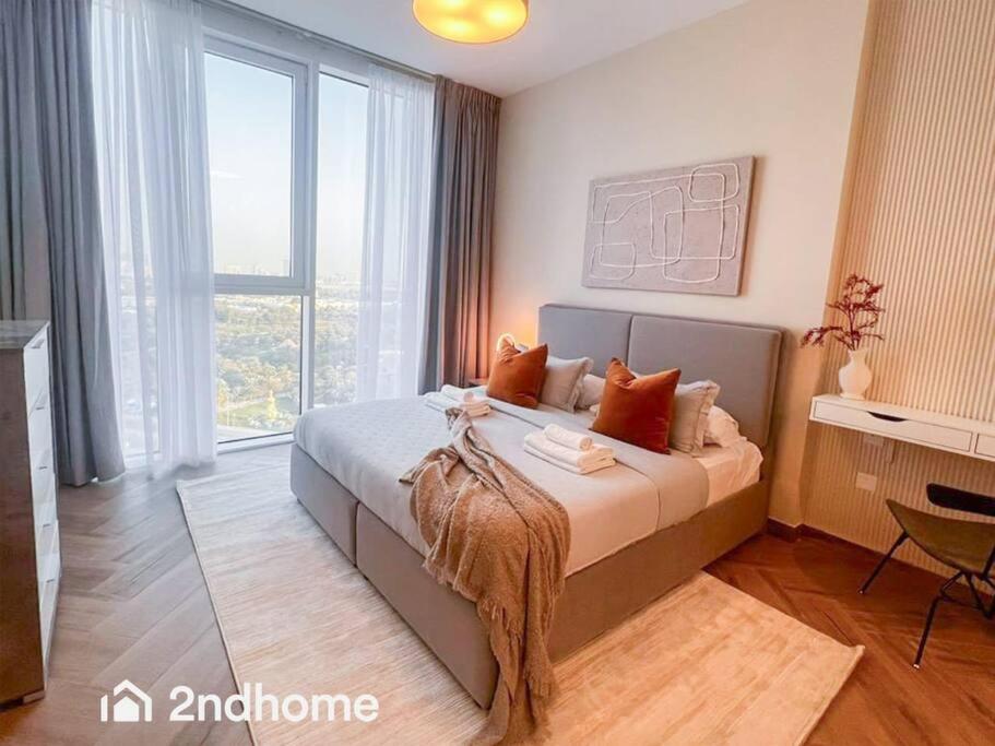 a bedroom with a large bed and a large window at Homey 1 Bedroom with Relaxing Zabeel Park View in Dubai