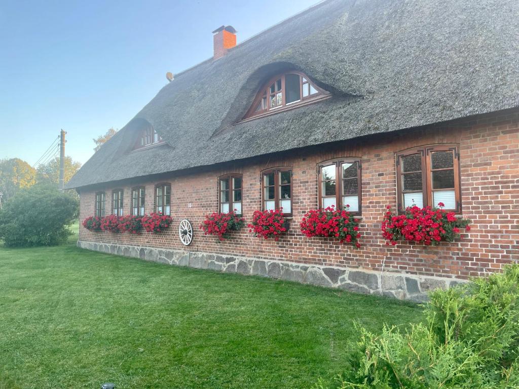 une maison en briques avec des fleurs rouges dans les fenêtres dans l'établissement Ferienwohnung Familie Manthei, à Boitin Resdorf