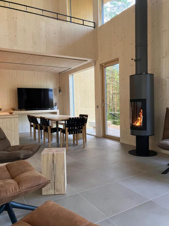 a living room with a fireplace and a dining table at Havu Resort Laajavuori, a calm and peasefull place in the forest near city in Jyväskylä