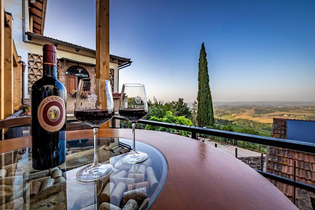 two glasses of wine sitting on a table on a balcony at Agriturismo Cesani in San Gimignano