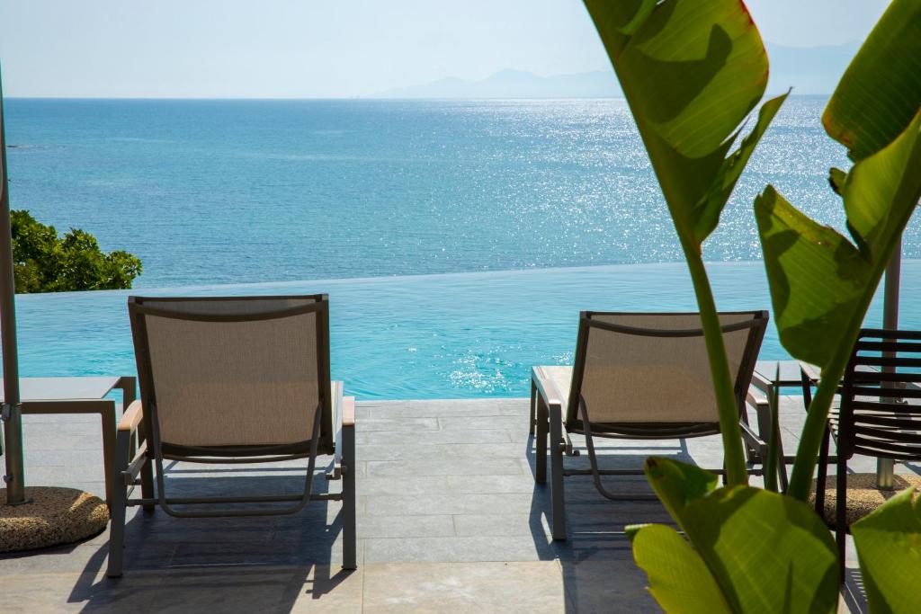 2 Stühle und ein Tisch mit dem Meer im Hintergrund in der Unterkunft Anasa Luxury Resort in Elaiokhórion