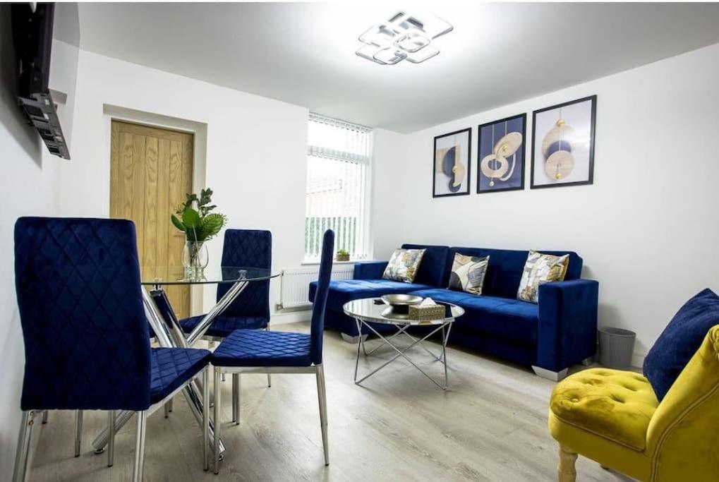 a living room with a blue couch and a glass table at Cosy Cruise Cribs Ltd in Stoke on Trent