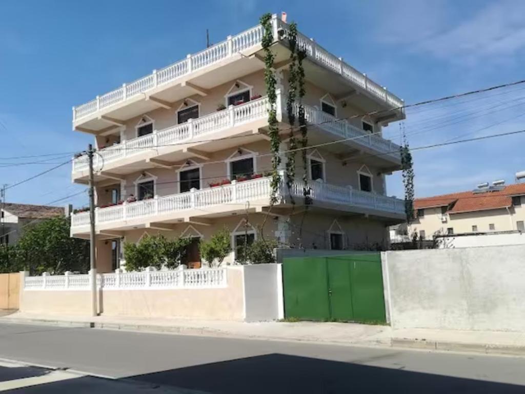un bâtiment blanc avec une porte verte en face dans l'établissement Vila Lika Durres, à Durrës