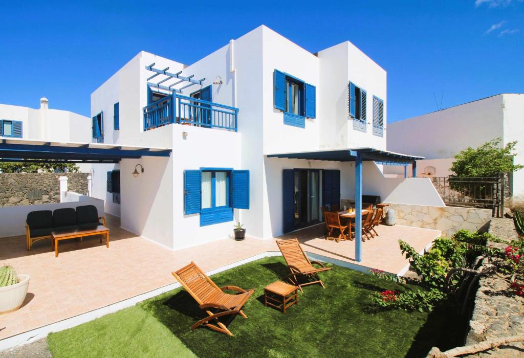 een groot wit huis met een tuin met stoelen bij Casa Bahia de Naos con vistas al mar in Arrecife