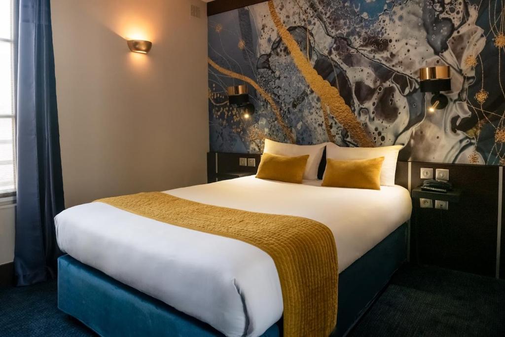 een hotelkamer met een groot bed met gele kussens bij Hôtel du Parc Montparnasse in Parijs