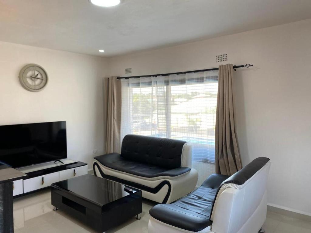 a living room with a couch and a tv at Swiss Luxury Apartments in Ndola