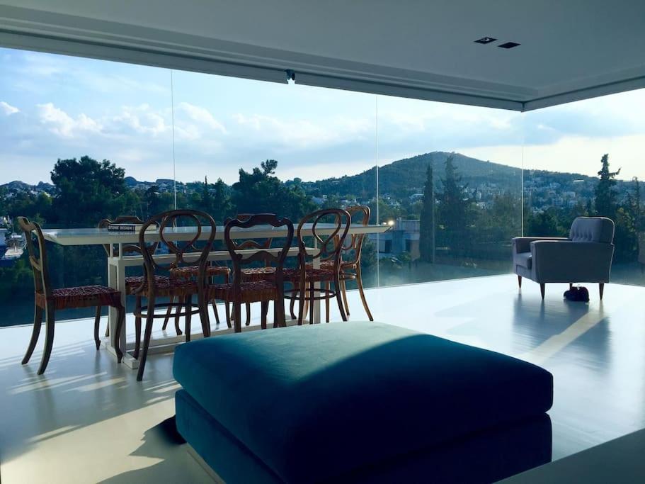 een eetkamer met een tafel en stoelen en een groot raam bij luxury ph private pool+roof garden in Athene