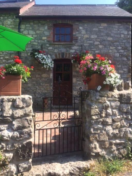 a stone house with a gate and flowers on it at 1 Bed cottage The Stable at Llanrhidian Gower with sofa bed for additional guests in Swansea