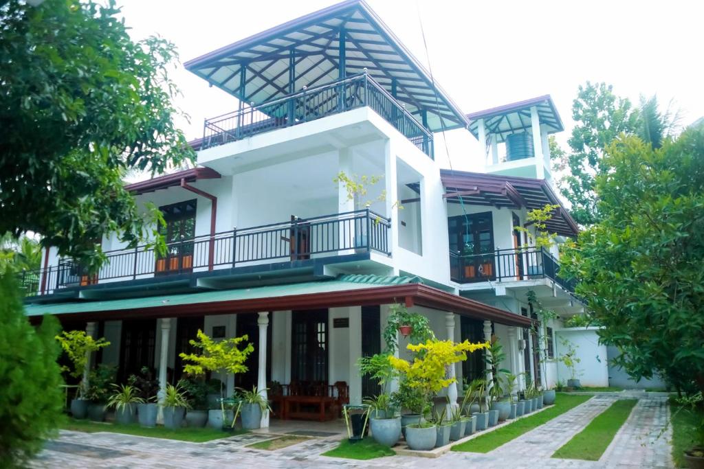 Casa blanca con balcones y árboles en Sunset Villa, en Tissamaharama