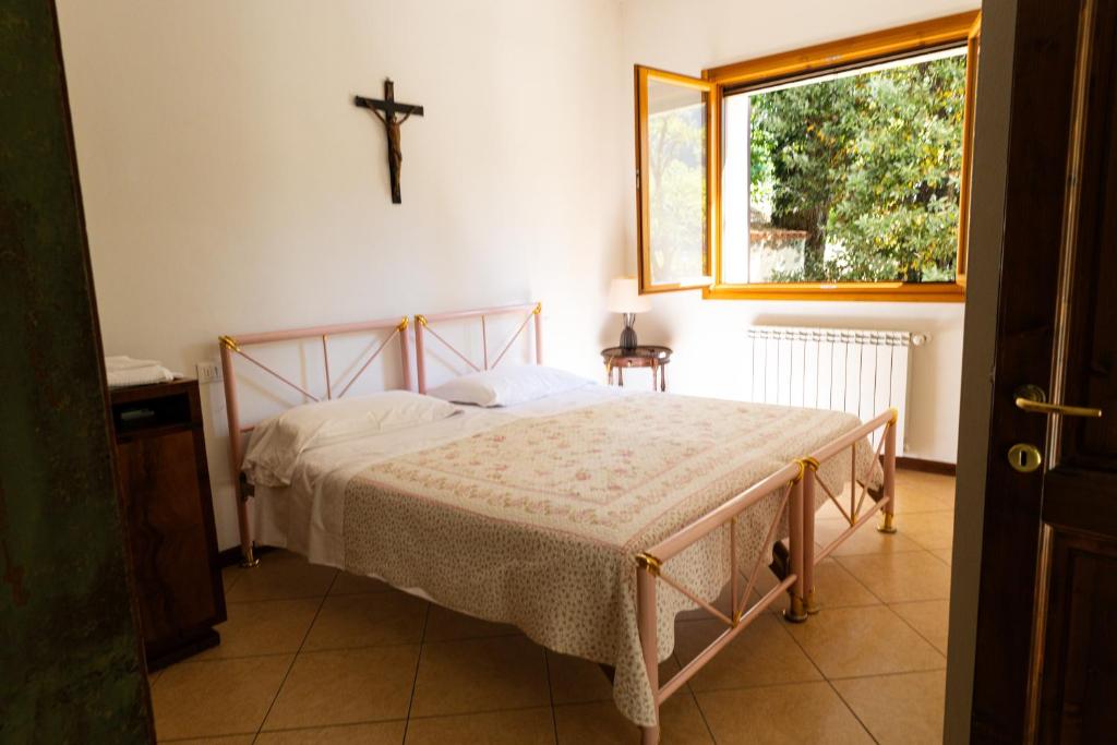a bedroom with a bed with a cross on the wall at Podere Riosto Cantina&Agriturismo in Pianoro
