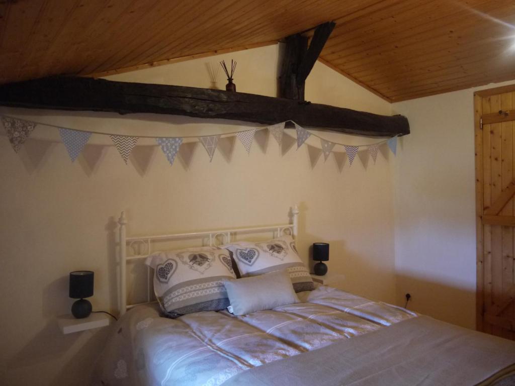 une chambre avec un lit avec un plafond en bois dans l'établissement Honeysuckle Cottage at Gites de la Vienne, à Chaunay