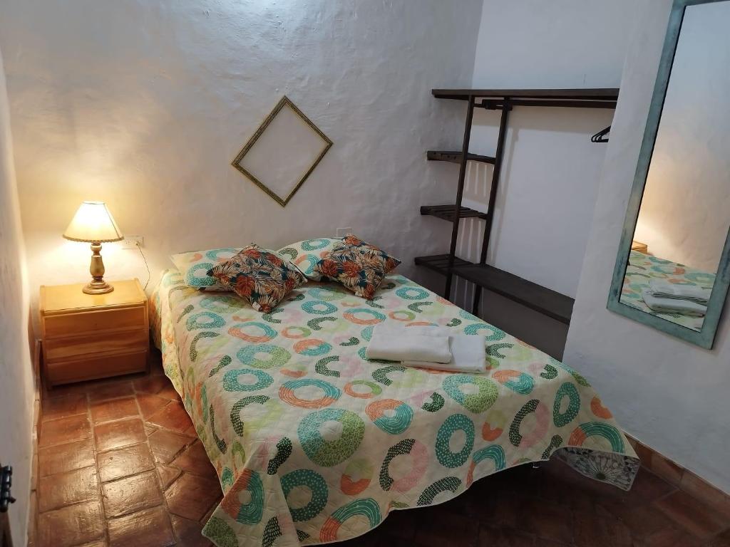 a bedroom with a bed with a lamp and a mirror at Casa Hostal Colonial VaraEchada in Barichara