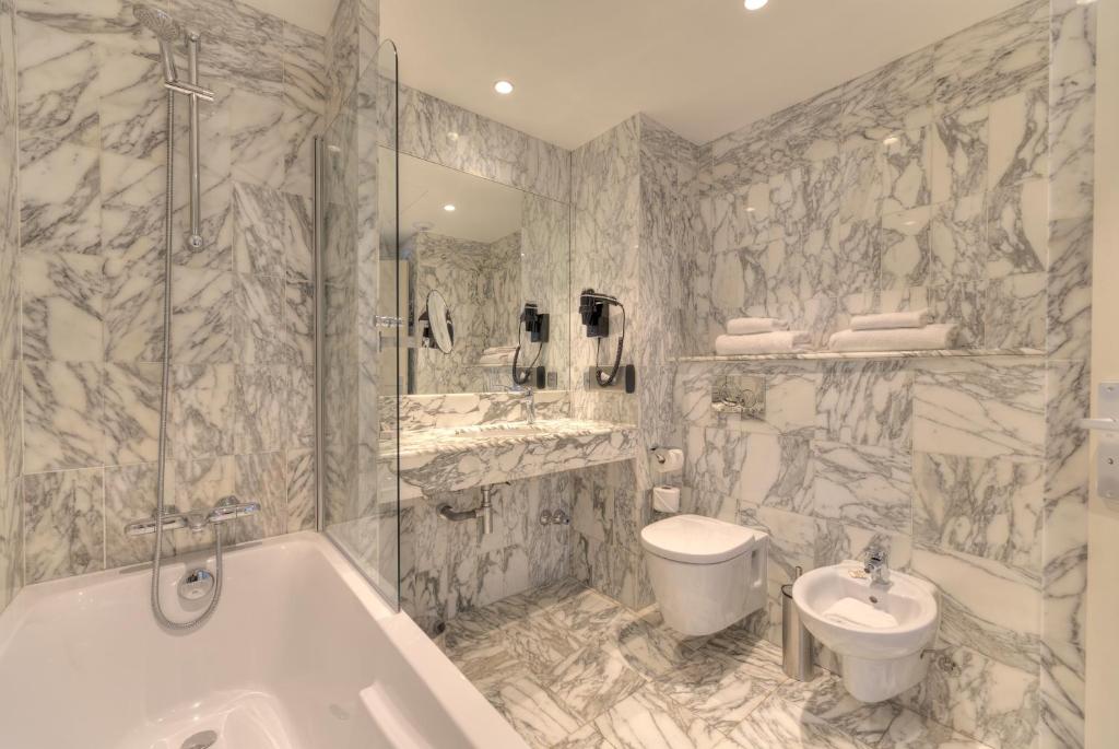 a bathroom with a tub and a sink and a toilet at Westminster Hotel & Spa Nice in Nice