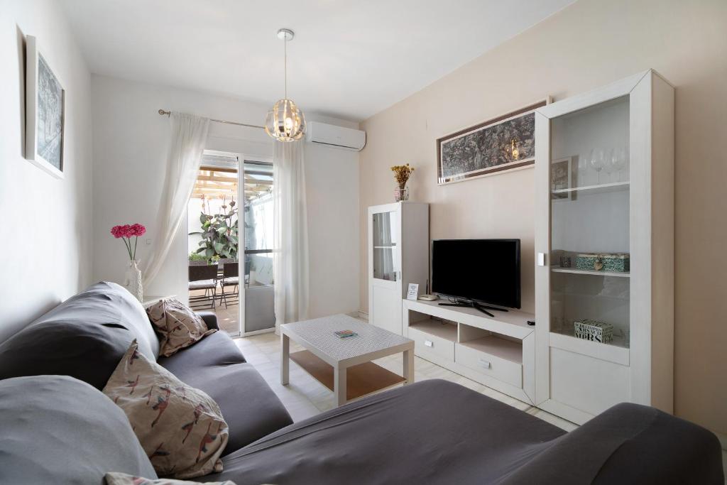 ein Wohnzimmer mit einem Sofa und einem TV in der Unterkunft San jeronimo in Sanlúcar de Barrameda