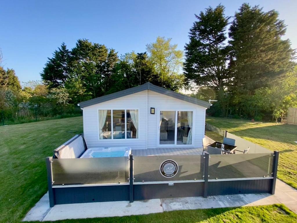 ein winziges Haus auf einem Wohnwagen im Hof in der Unterkunft The Retreat 22 - Hot Tub Lodge, pet friendly, WiFi - Golden Palm Resort - Meadow Lakes Caravan & Lodge Hire in Skegness