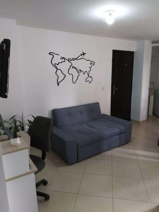 eine blaue Couch in einem Wohnzimmer mit einer Karte an der Wand in der Unterkunft MALAGA in Sabaneta