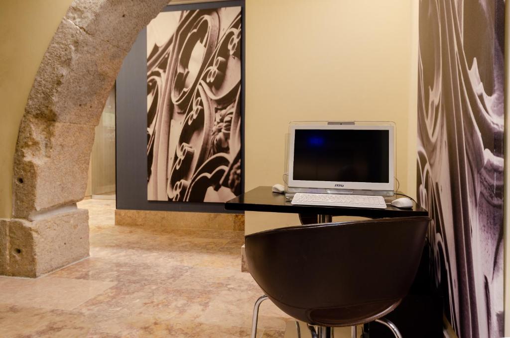 A small black desk provides a laptop, monitor and mouse in a decorated interior nook.