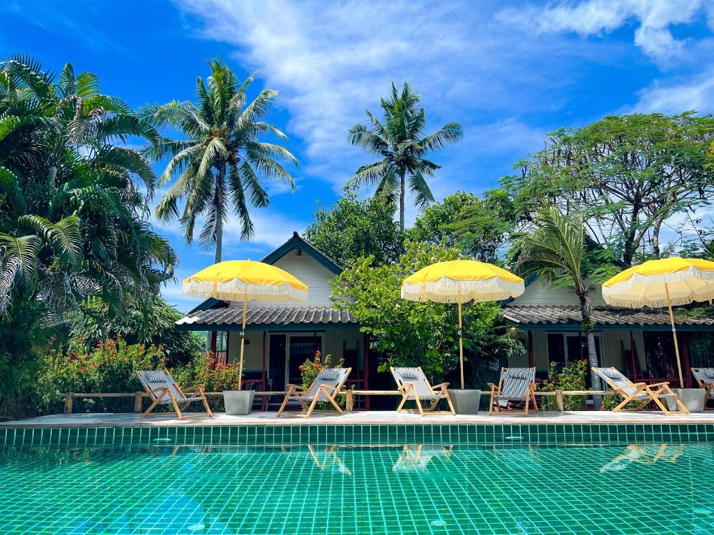 a villa with a swimming pool and umbrellas at Oasis Yoga Bungalows in Ko Lanta