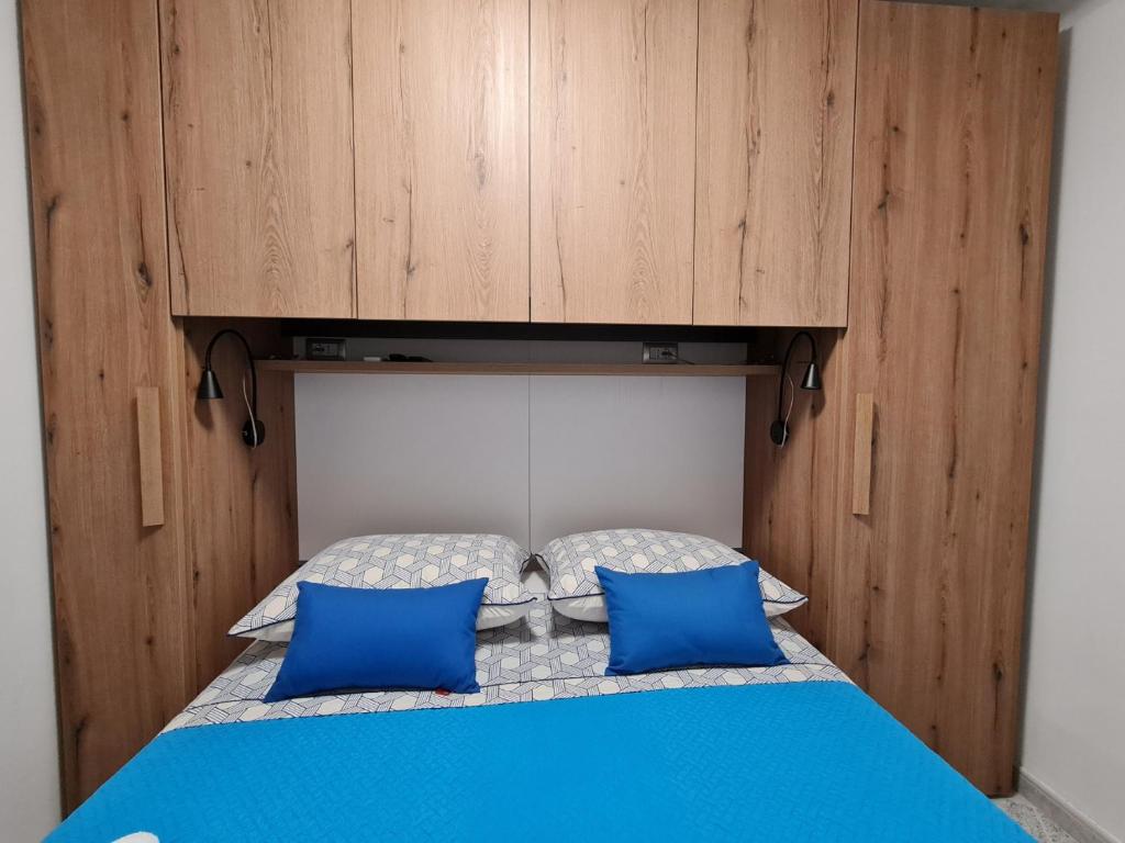 a bed with blue pillows and a cabinet above it at Studio Arsenale 7 in Rovinj