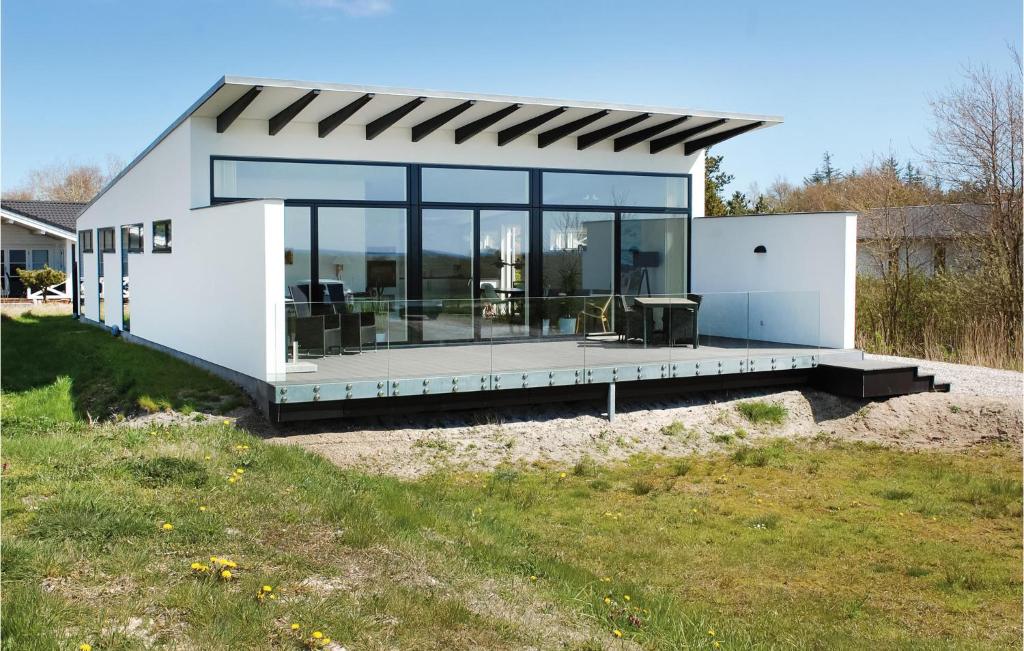 エーベルトフトにあるAmazing Home In Ebeltoft With House Sea Viewの大きなガラス窓のある小さな白い家