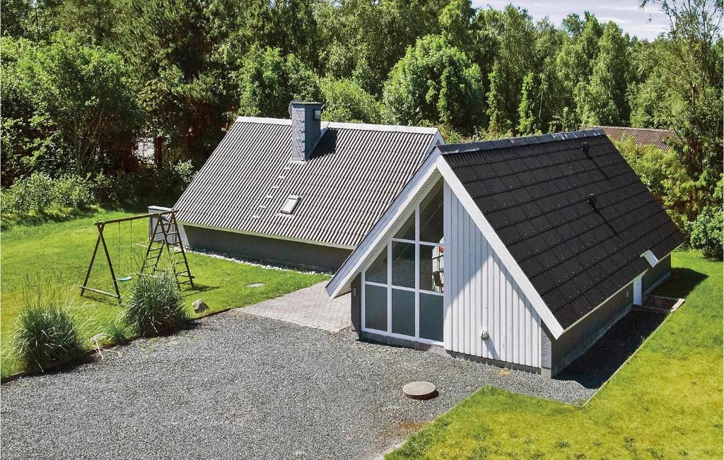 una pequeña casa con techo de gambrel y parque infantil en Cozy Home In Ebeltoft With Outdoor Swimming Pool, en Ebeltoft