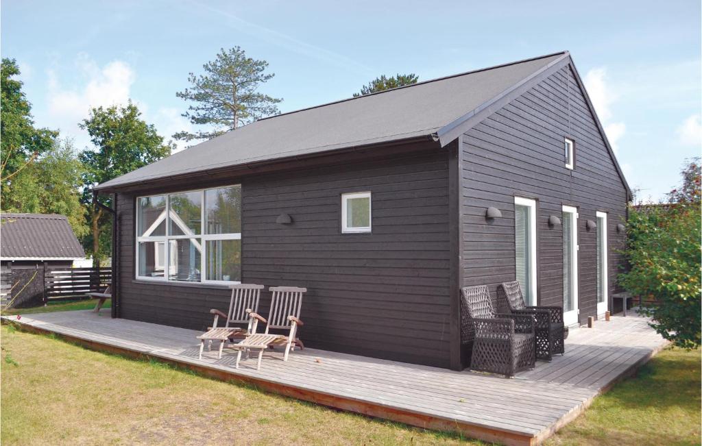 エーベルトフトにあるStunning Home In Ebeltoft With 3 Bedrooms And Wifiの木製デッキの椅子付き黒キャビン
