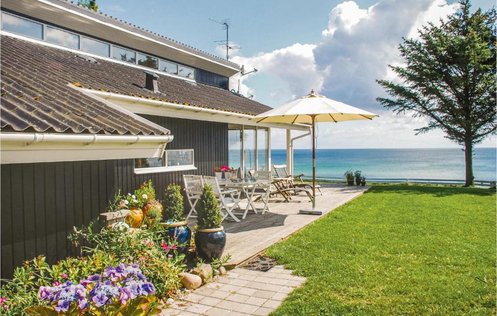 エーベルトフトにあるGorgeous Home In Ebeltoft With Kitchenの海の景色を望むパティオ(テーブル、傘付)