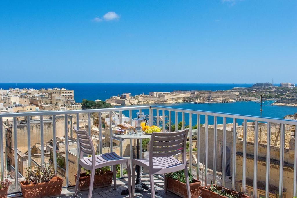 Valletta Apartments 19 في فاليتا: شرفة مع كراسي وطاولة مطلة على الشاطئ