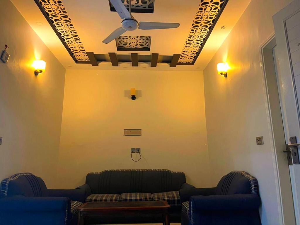 a living room with two couches and a ceiling fan at Elegant Guest House Karachi in Karachi