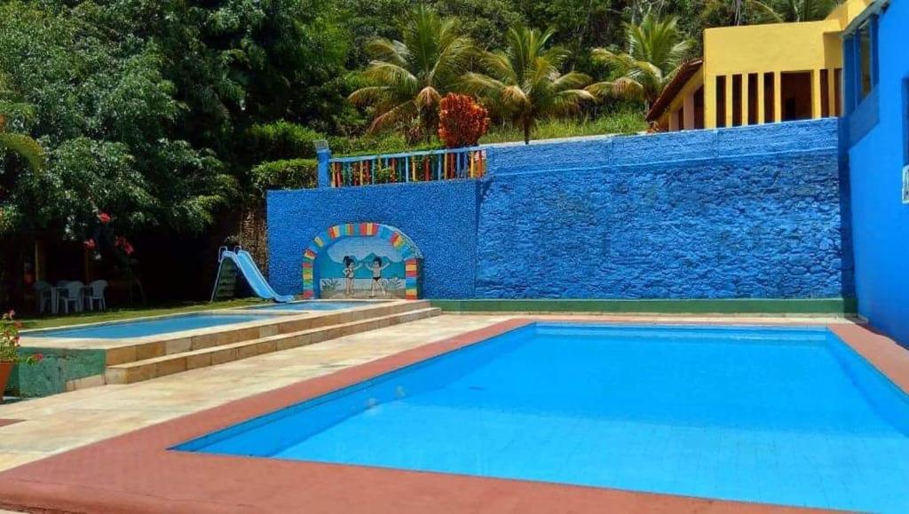 a blue swimming pool with a slide next to a house at Hotel Gruta da Serra in Guaramiranga