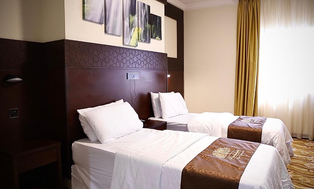 two beds in a hotel room with white sheets at فندق الفجر البديع واحد للخدمات الفندقيه in Al Khansāk