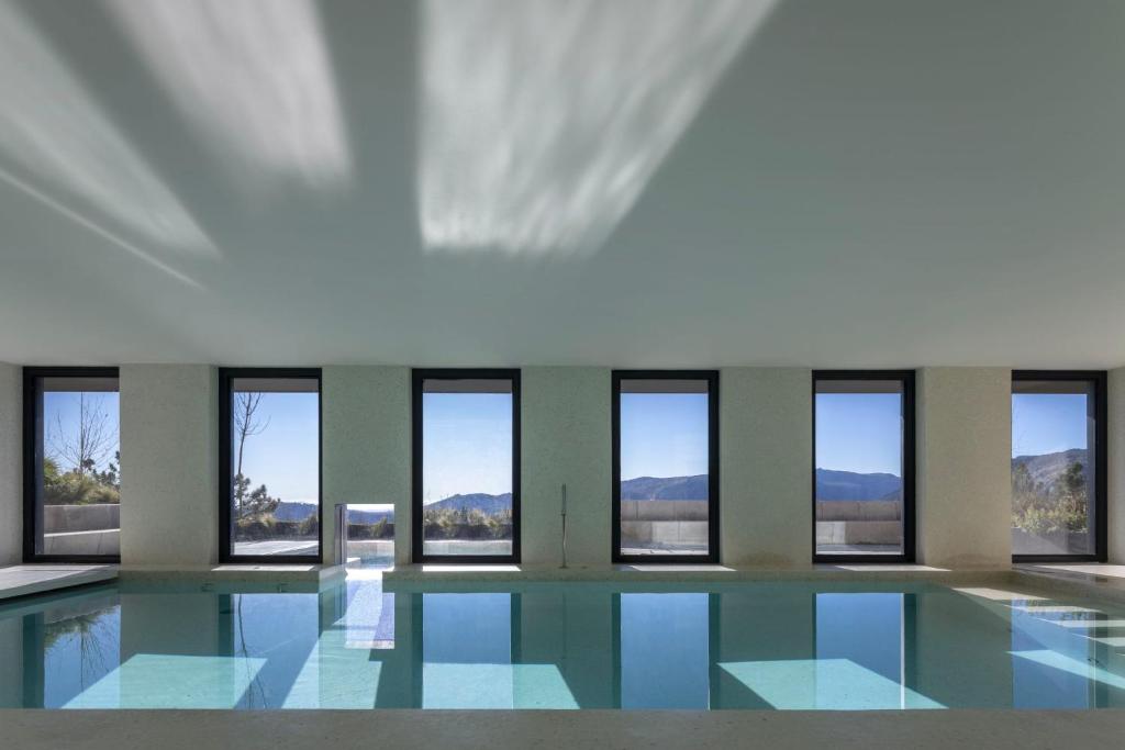 a swimming pool with windows in a building at Casa de São Lourenço - Burel Mountain Hotels in Manteigas