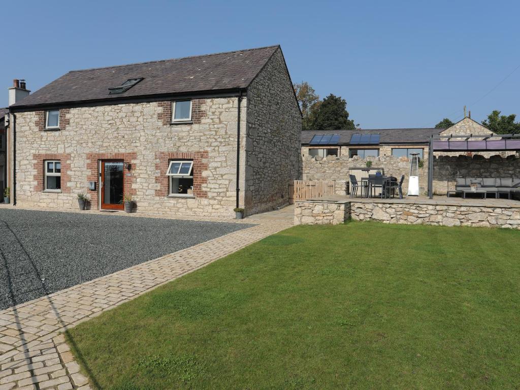 an external view of a stone house with a yard at The Stables in Beaumaris