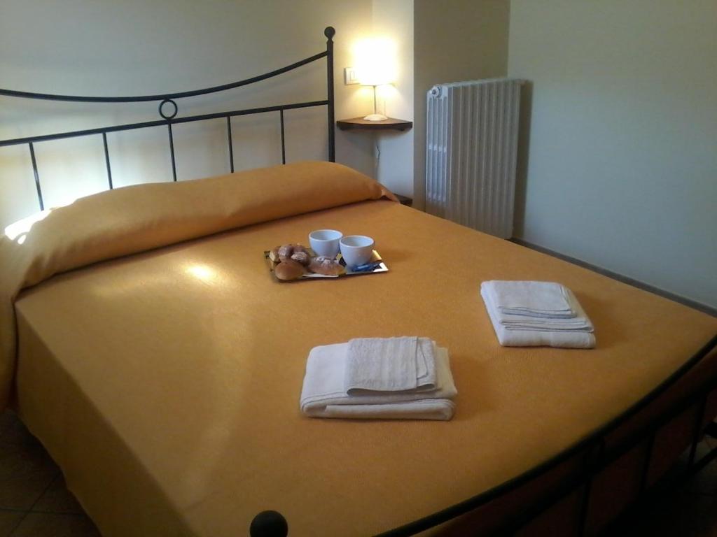 una cama con toallas, dos tazas y un osito de peluche. en Agriturismo Valiana, en Montegabbione