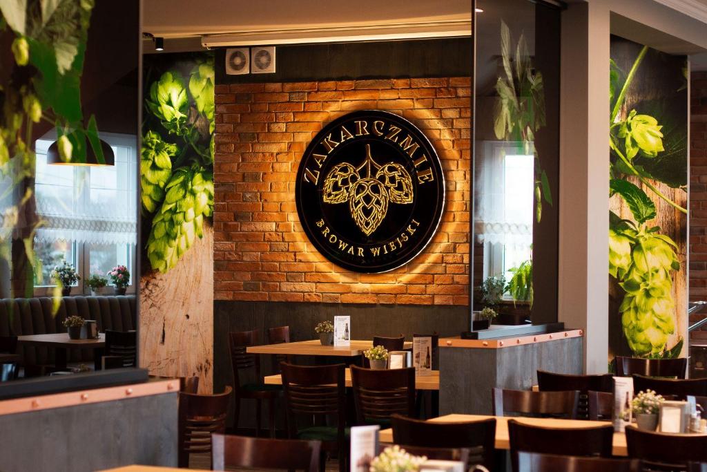 a restaurant with tables and chairs and a clock on a brick wall at Zakarczmie Stokrotka in Leżajsk