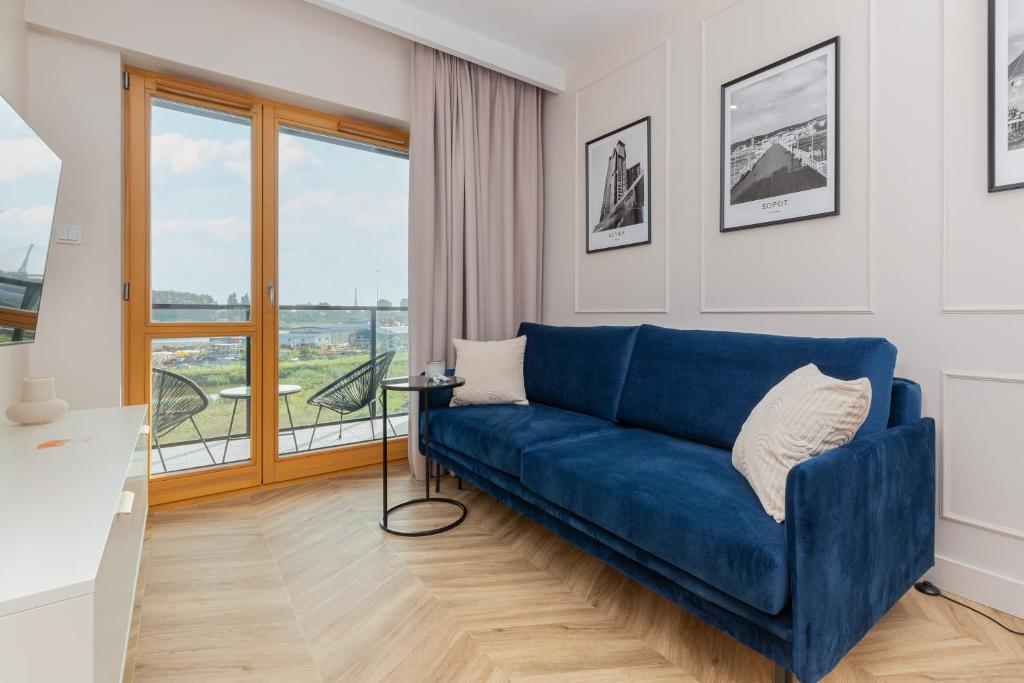 a blue couch in a living room with a window at Sienna Grobla Apartment View of the Motława by Renters in Gdańsk