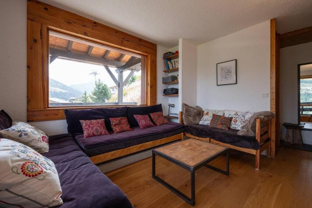 ein Wohnzimmer mit einem lila Sofa und einem Fenster in der Unterkunft L'Arc-en-Ciel - Appartement sur les hauteurs du Mottaret avec accès aux pistes in Les Allues