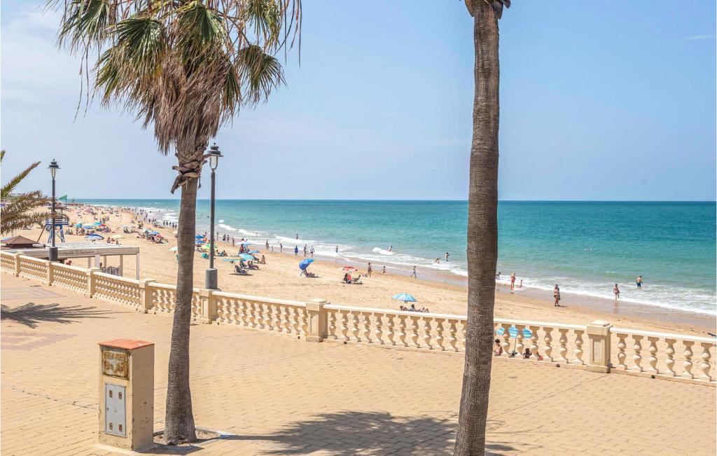 una playa con palmeras y gente en la playa en Beautiful Apartment In Chipiona With Kitchenette en Chipiona