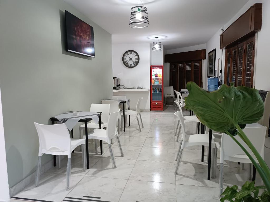 a restaurant with white chairs and a clock on the wall at Hotel FG in Termas de Río Hondo