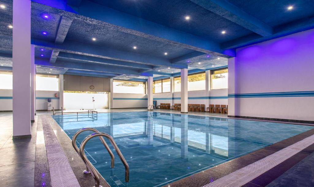 a large indoor pool with blue lighting in a building at Treebo Trend The Rove in Madikeri