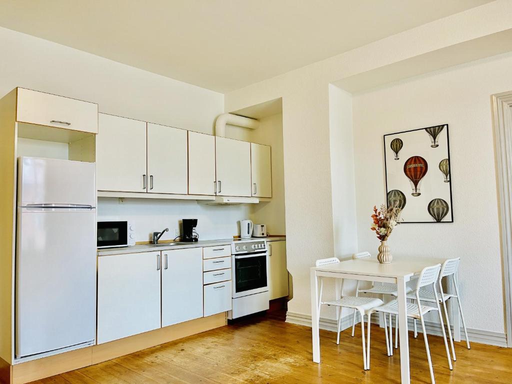 uma cozinha com um frigorífico branco e uma mesa em aday - Sunshine apartment in the heart og Hjorring em Hjørring