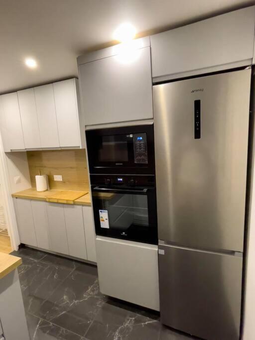 a kitchen with a stainless steel refrigerator and a microwave at Magnifique appartement de 4 chambres 8 personnes max à 20 minutes de Paris in Antony